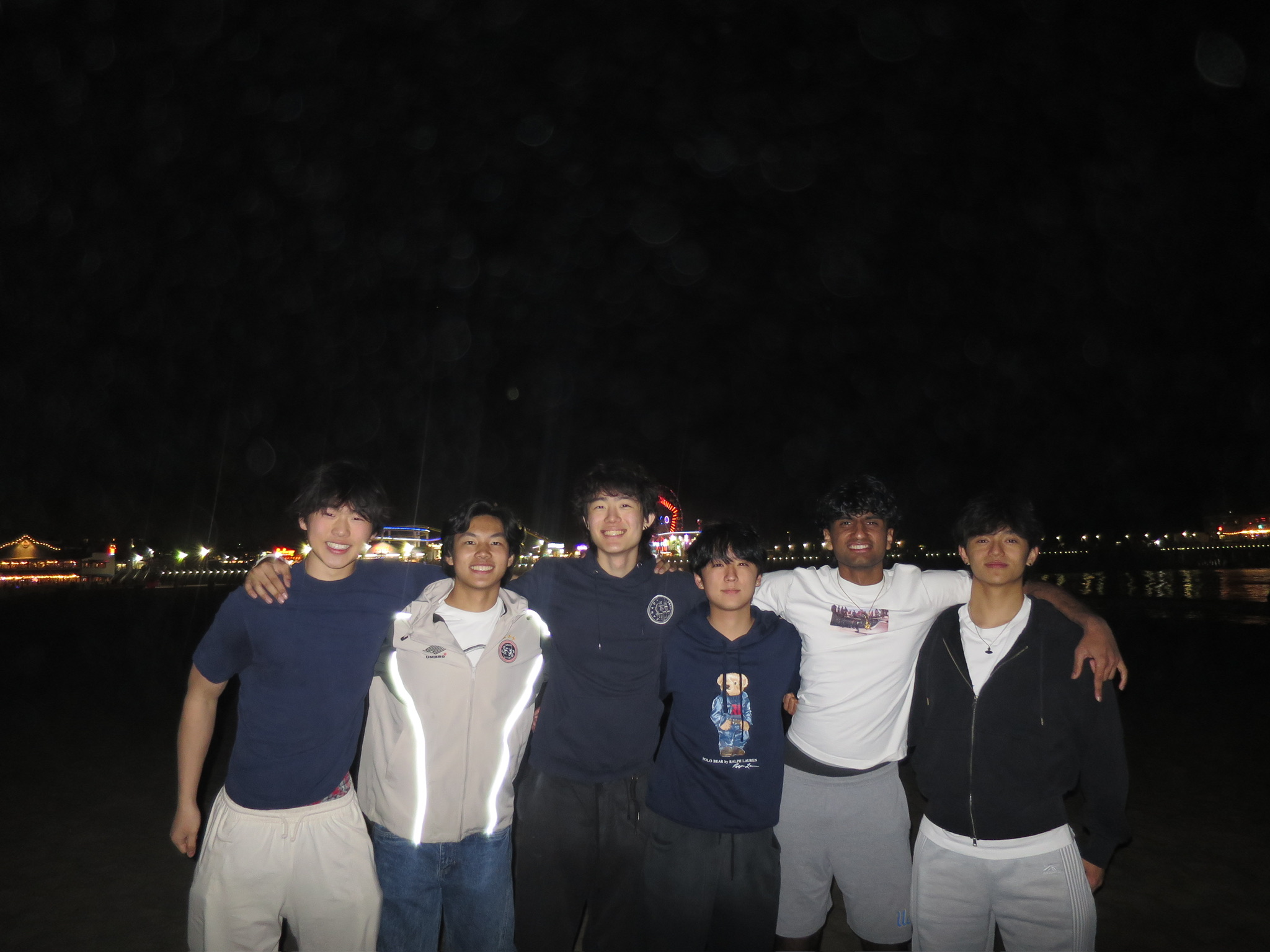 UCLA Delta Sigma Pi active brothers together by the pier at night